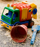 En leksakslastbil, en spann och en spade ligger i sandlådan.