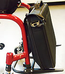 Väskhållaren monterad på en rullstol. Ser ut lite som rullstolen byggts om till gaffeltruck.