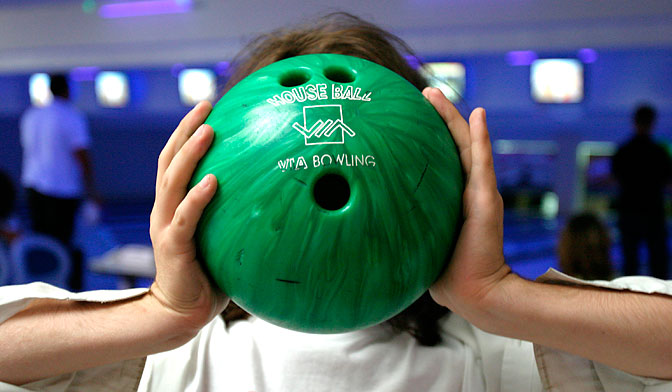 En person håller ett bowlingklot framför ansiktet